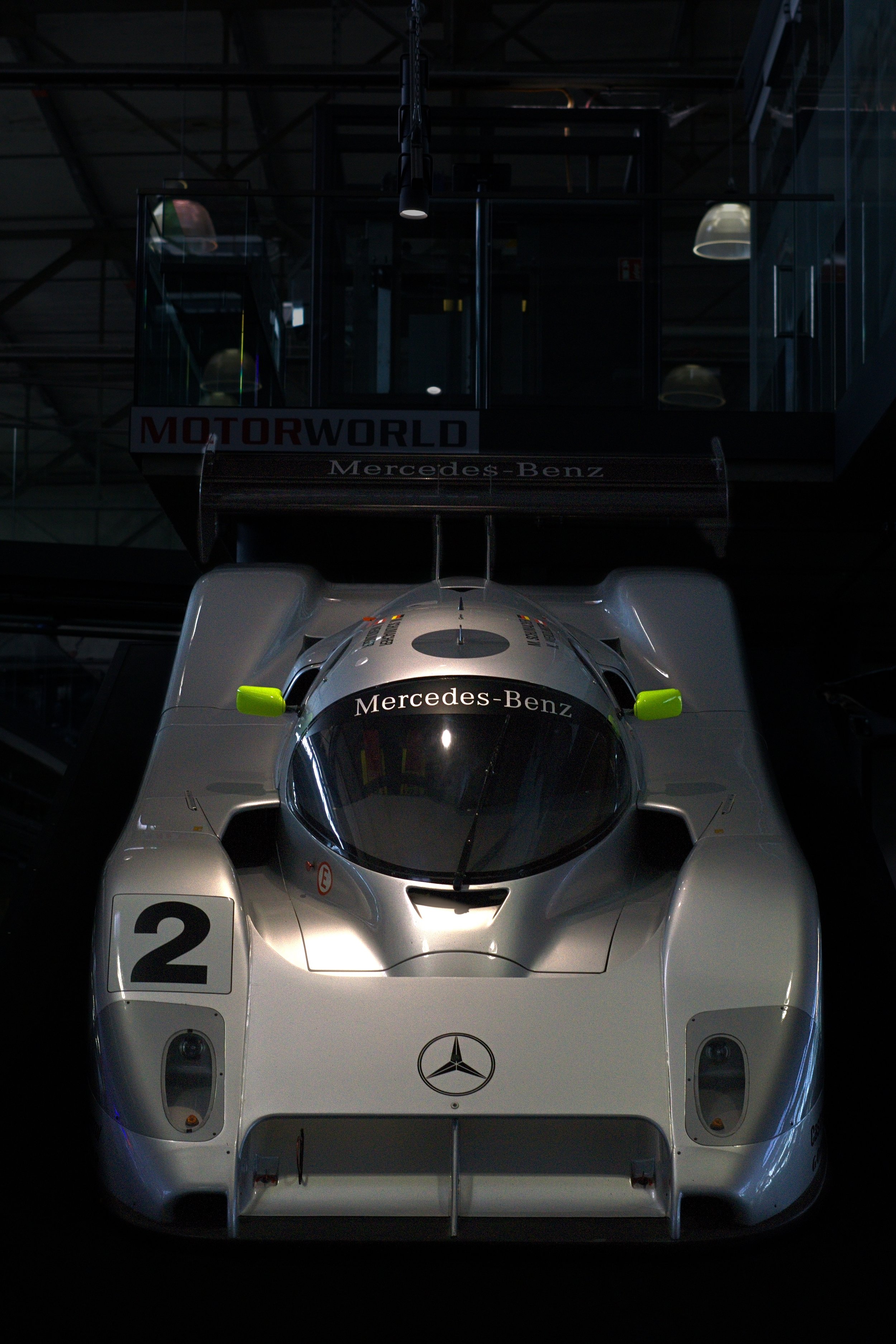 Ein silberner Mercedes-Benz Rennwagen im Dunkeln bei einer Ausstellung.