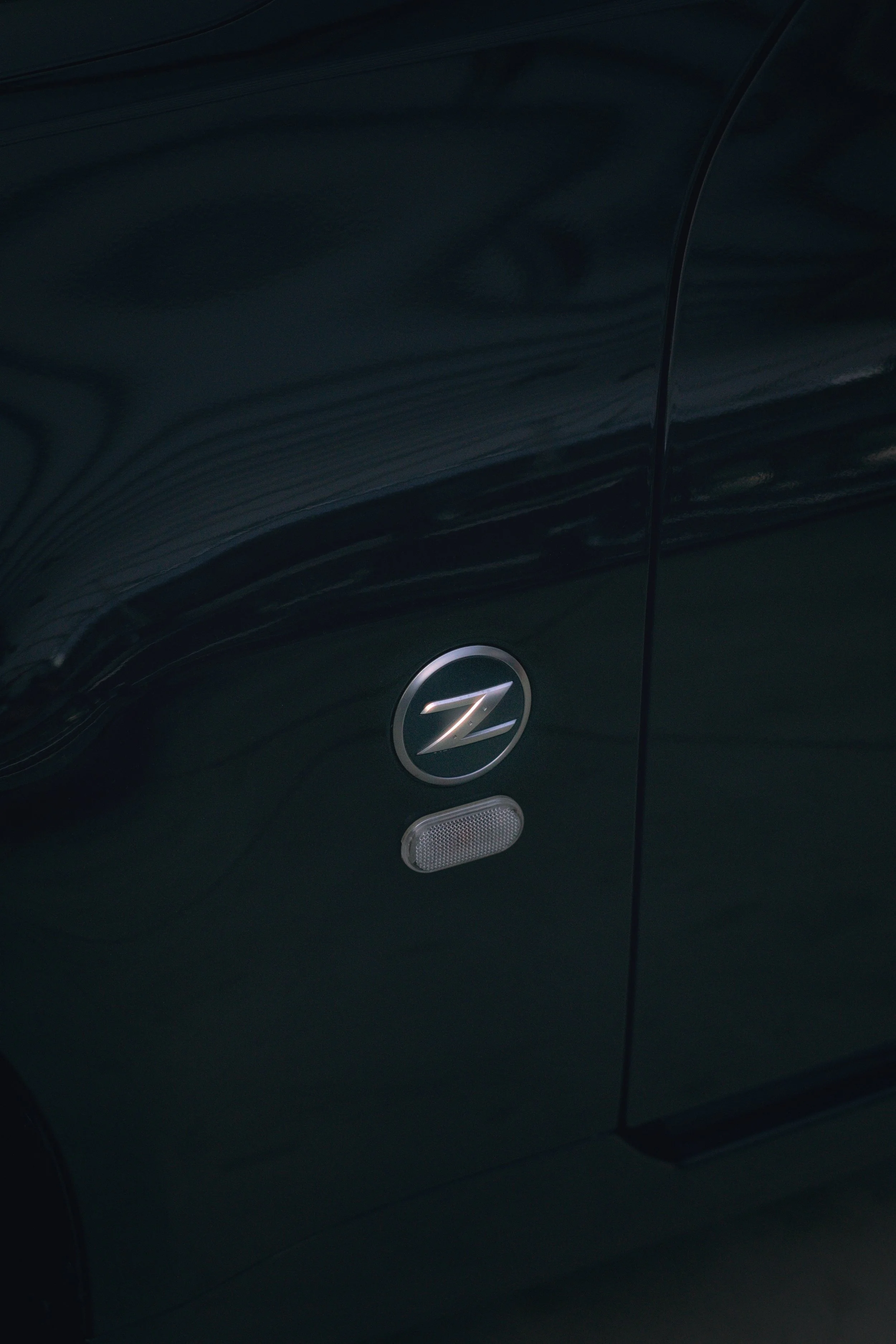 Nahaufnahme eines schwarzen Fahrzeugs mit einem Z-Emblem und einer kleinen reflektierenden Leuchte daran.