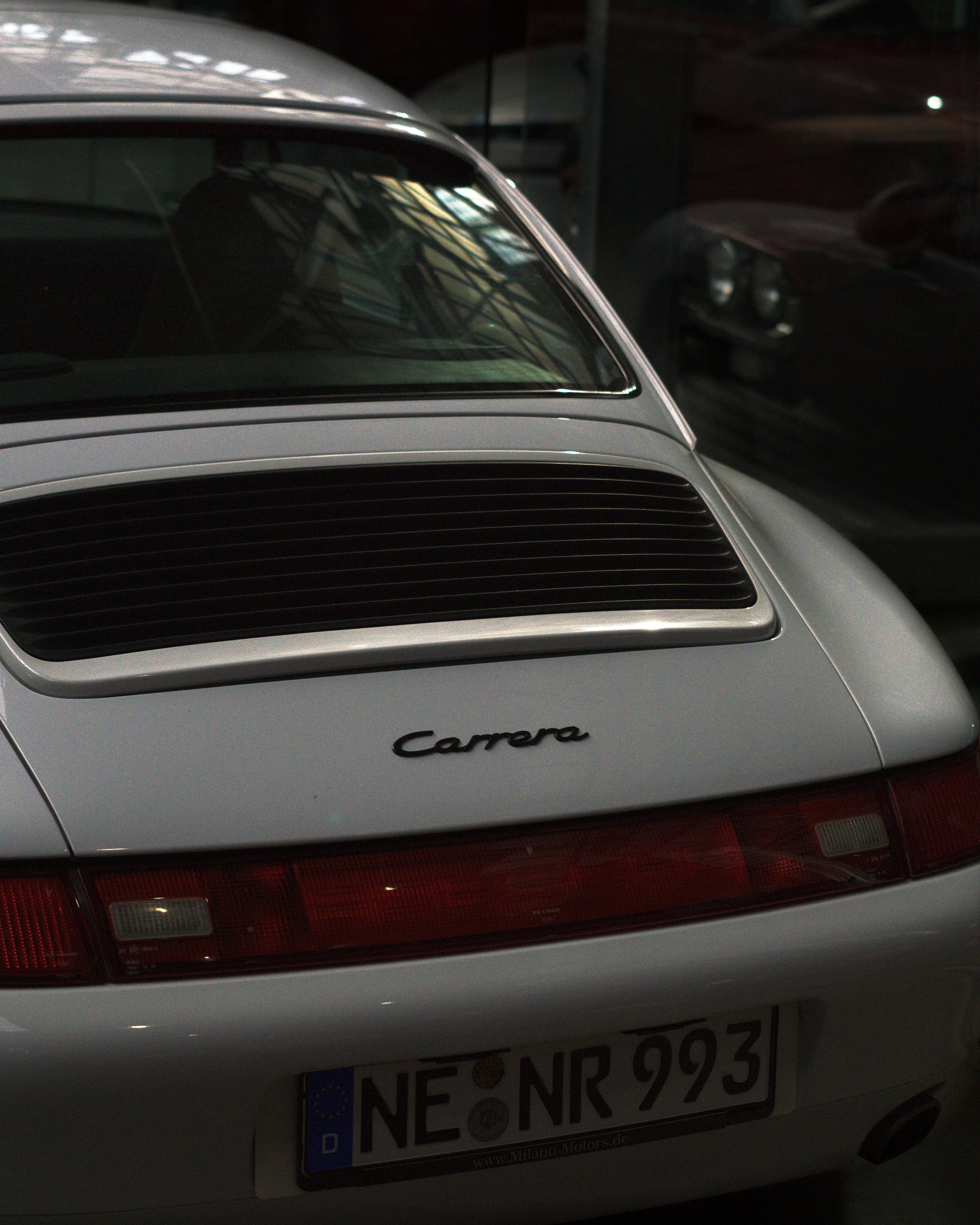 Vorderseite eines weißen Porsche 911 Carrera mit deutscher Nummerntafel