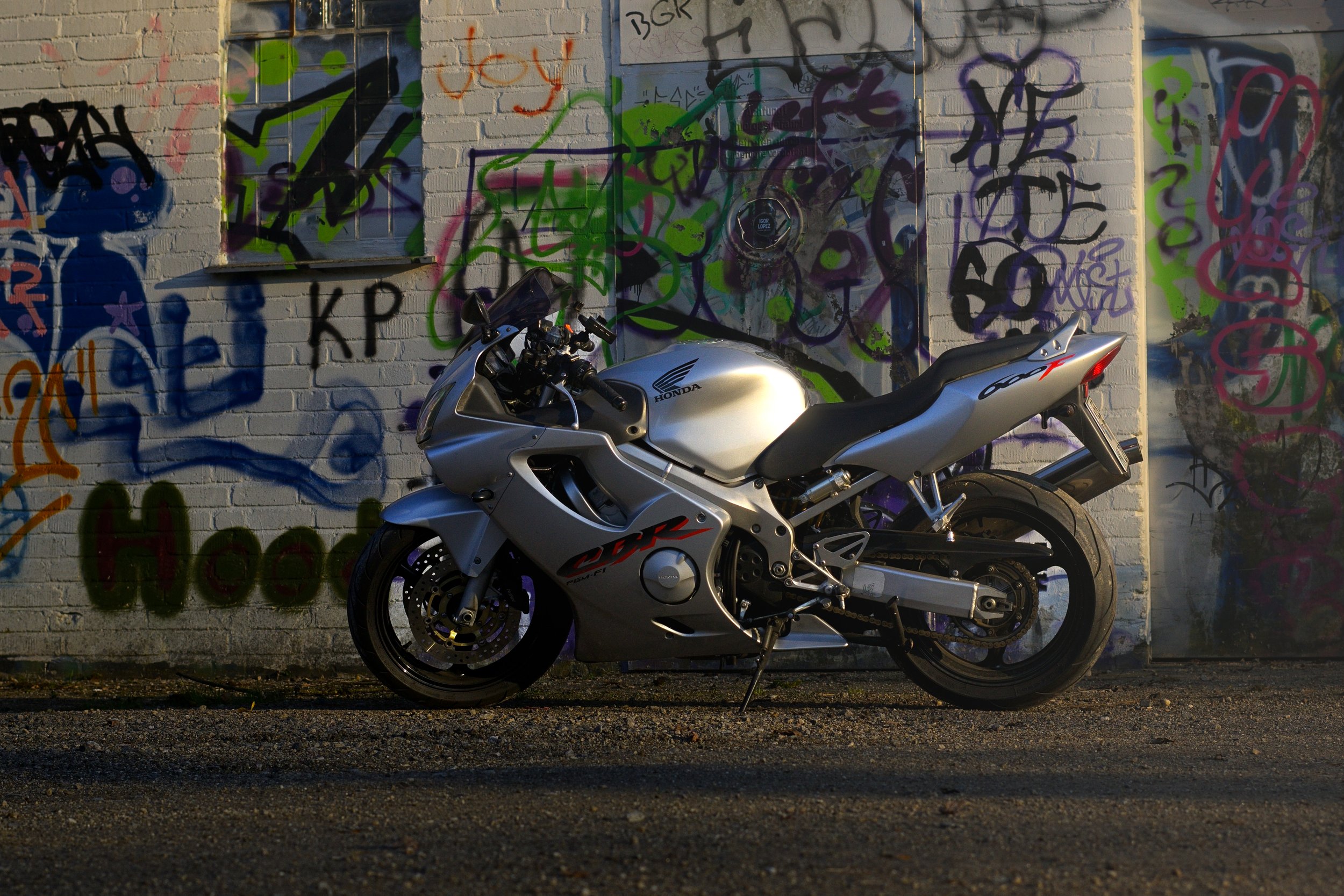Silberne Honda CBR Motorrad vor einer grauen, graffiti-verzierten Wand.