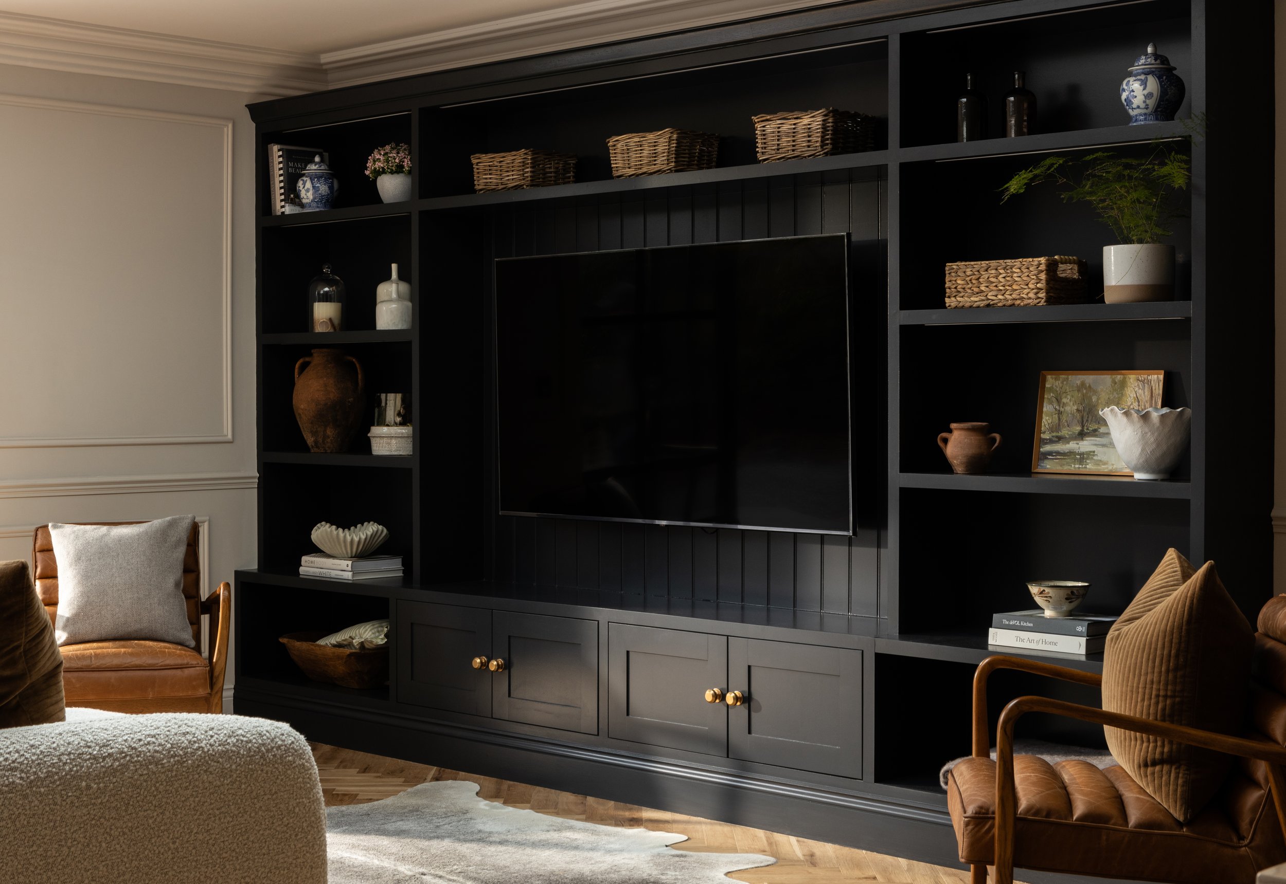 Living room with black entertainment center, decorative items, books, and seating area.