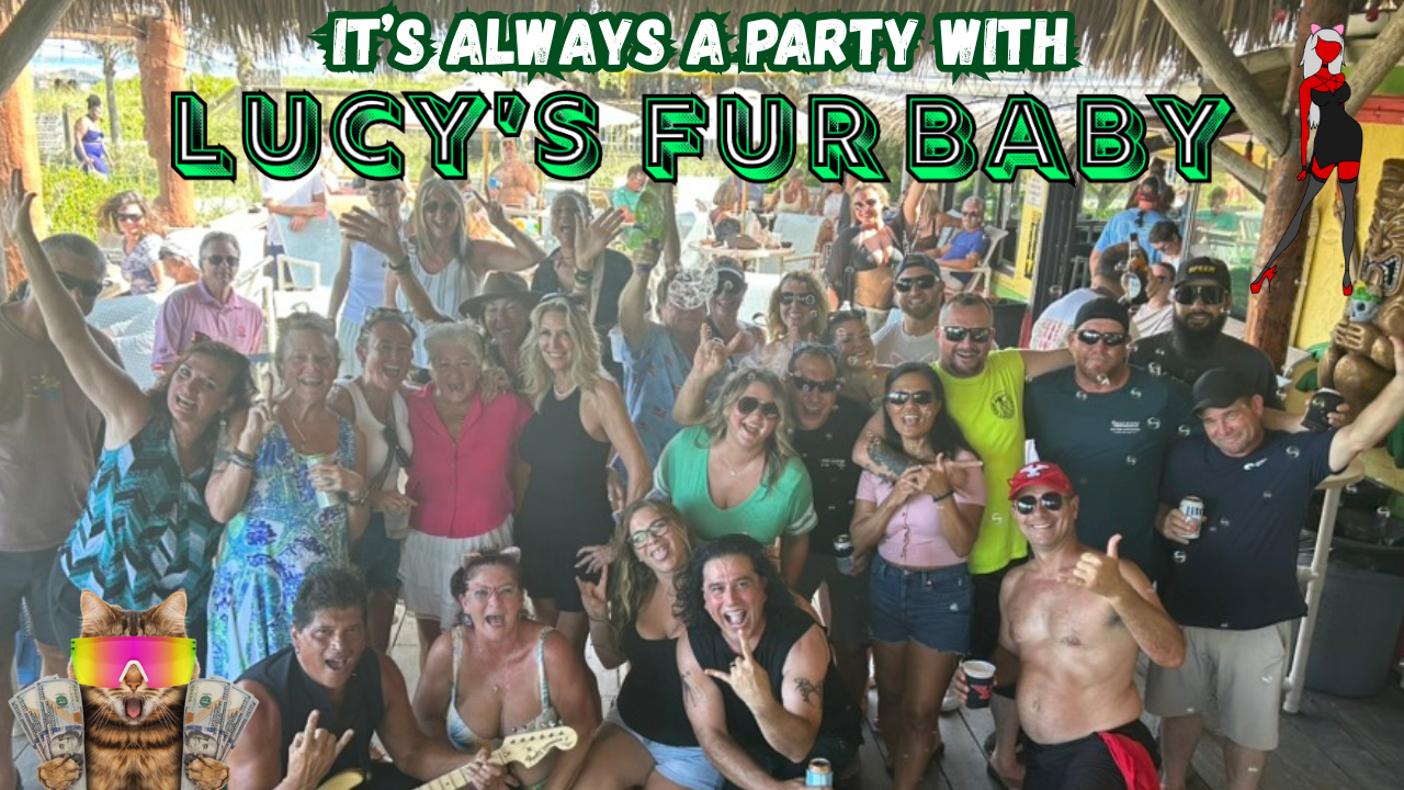 Group of people gathered outdoors at a party, smiling and posing for the camera, with a colorful banner that reads "It's always a party with Lucy’s Fur Baby" above them.