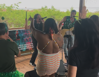 A group of people enjoying live music outdoors, surrounded by a vibrant, casual atmosphere.