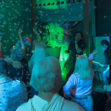 People dancing and enjoying music at a Lucy's Fur Baby party with green laser lights.