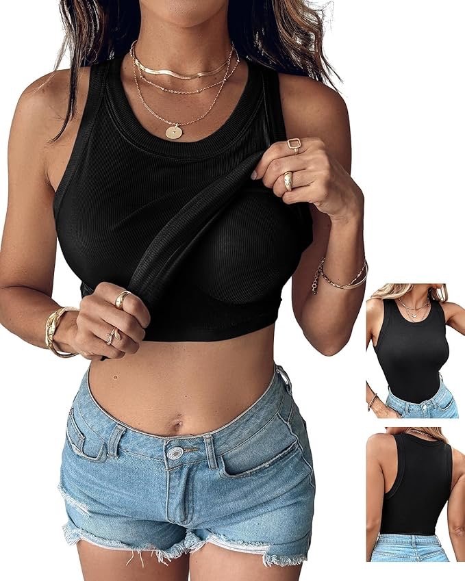 A woman wearing a black sleeveless crop top and light blue denim shorts, holding the strap of her crop top with her right hand. She has multiple necklaces and rings on her fingers, and is accessorized with bracelets on her left wrist.