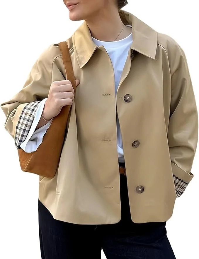 Close-up of a woman wearing a beige trench coat with checkered lining, white shirt, and carrying a brown shoulder bag.