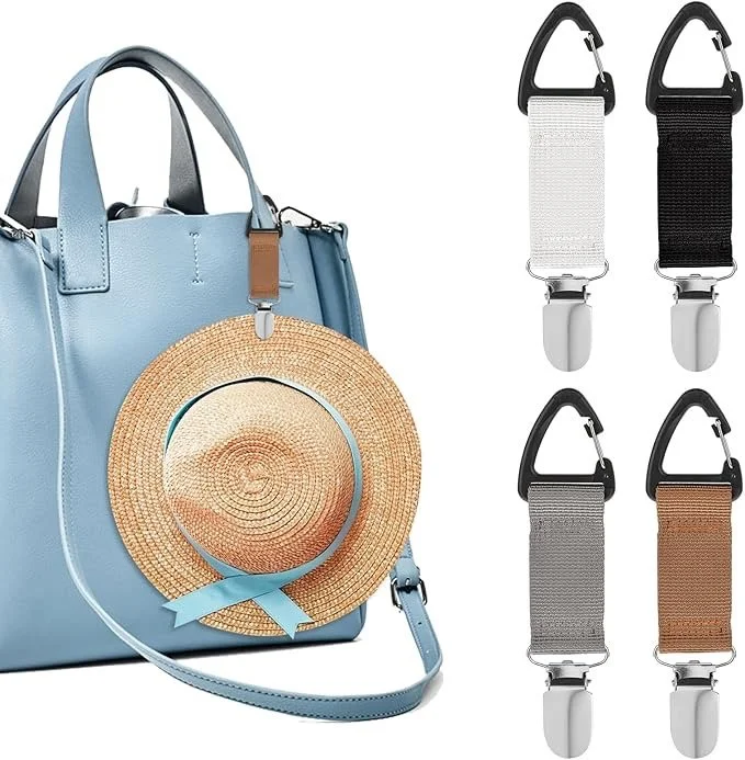 A blue tote bag with a woven straw hat hanging on it and four adjustable stroller clips in black, white, gray, and brown.