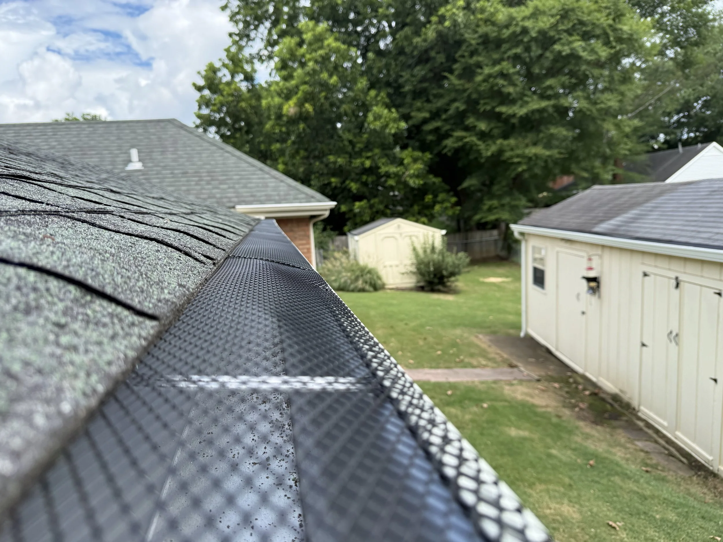 White seamless gutters with black gutter guards installed to improve rainwater drainage while helping keep leaves and debris out of the gutter system.