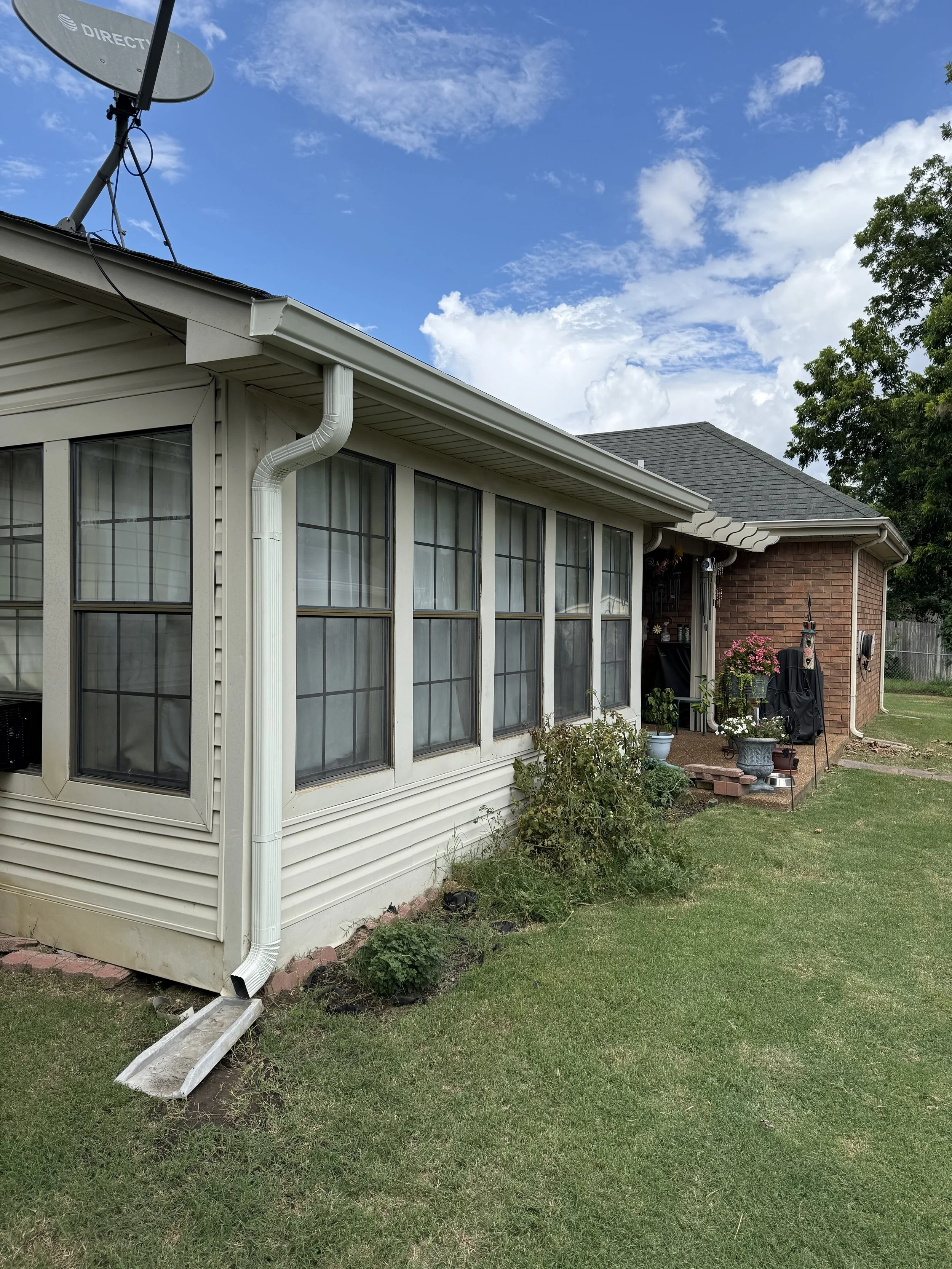 White seamless gutters with black gutter guards installed on a home in Olive Branch, MS, helping improve drainage while reducing leaves and debris.