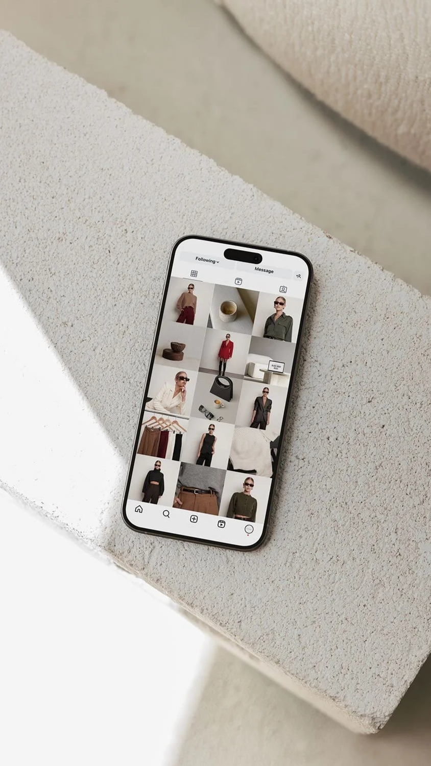 Smartphone displaying an Instagram profile with fashion photos, placed on a textured surface.
