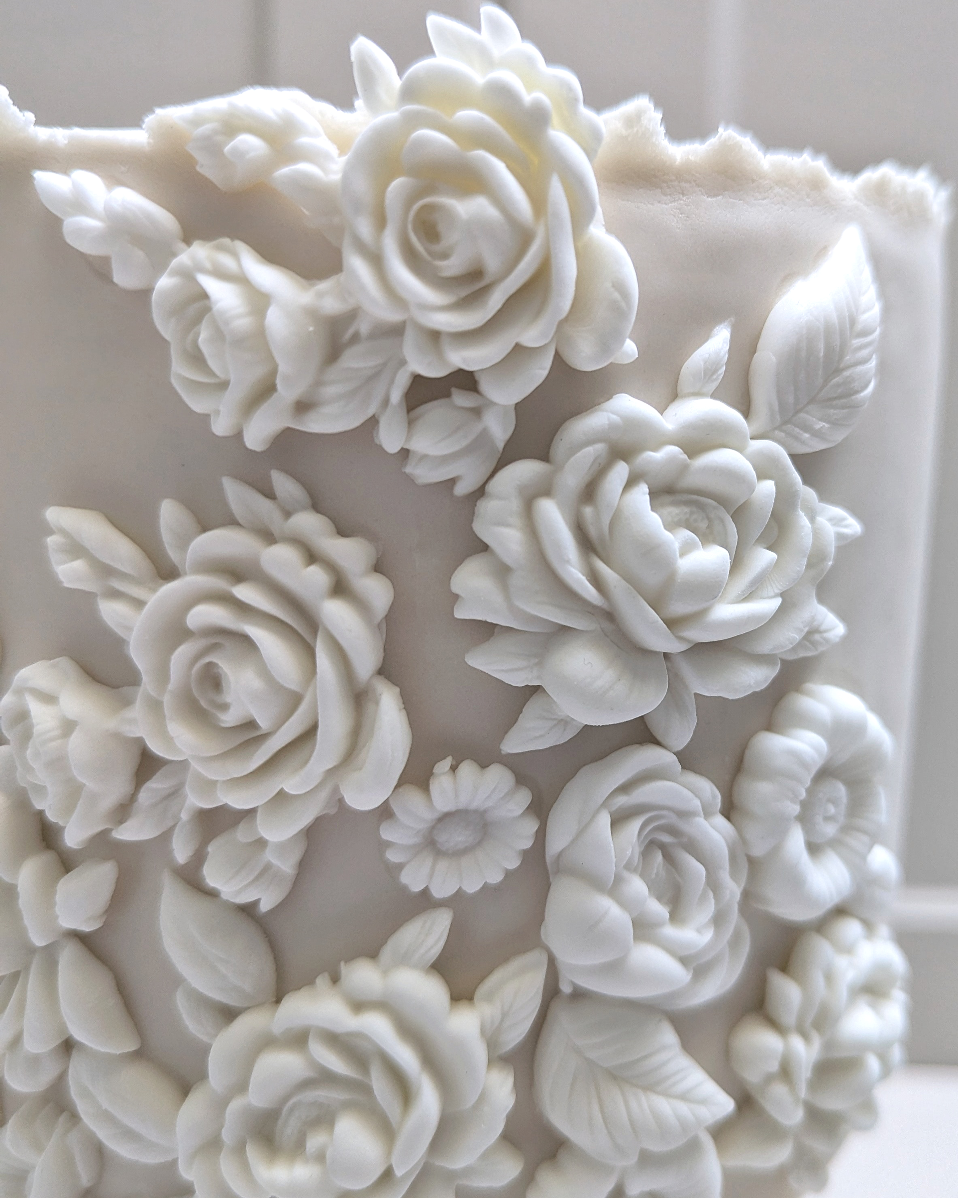 Stunning close-up of white decorative sugar flowers and leaves on a cake.