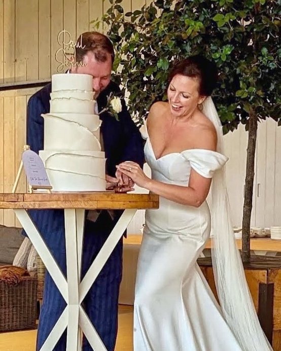 Gorgeous bride and groom cutting into their elegant 3 tier wedding cake. Venue: Primrose Hill Farm, Warwickshire.