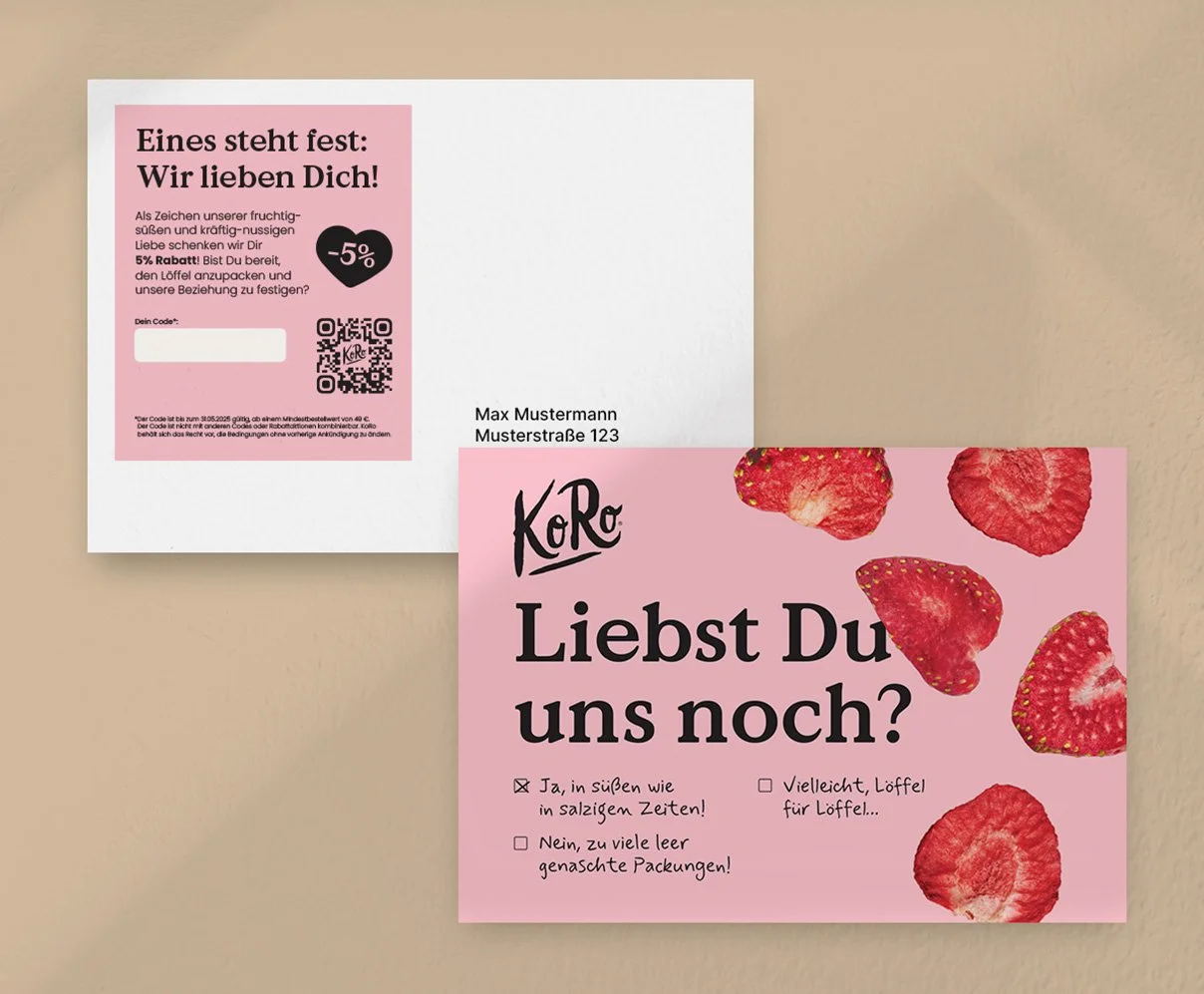 Zwei Verpackungen, eine mit Liebe- und Rabattinformationen, die andere eine rosa Karte mit Erdbeeren und der Frage 'Liebst Du uns noch?'