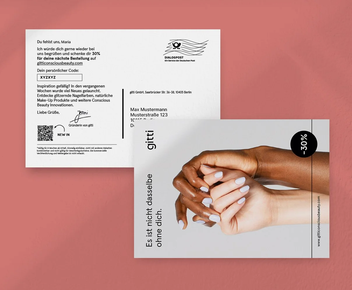 Zwei Werbebroschüren für eine Schönheits- und Nagelpflege-Website, die auf einer rosa Oberfläche liegen. Eine Broschüre zeigt ein Bild von zwei Hände, eine dunkle und eine helle, die sich halten, mit einem Rabatt-Hinweis von 30 %. Die andere Broschüre enthält einen Brief mit persönlichem Code, QR-Code und Angaben zur Marke gitti.