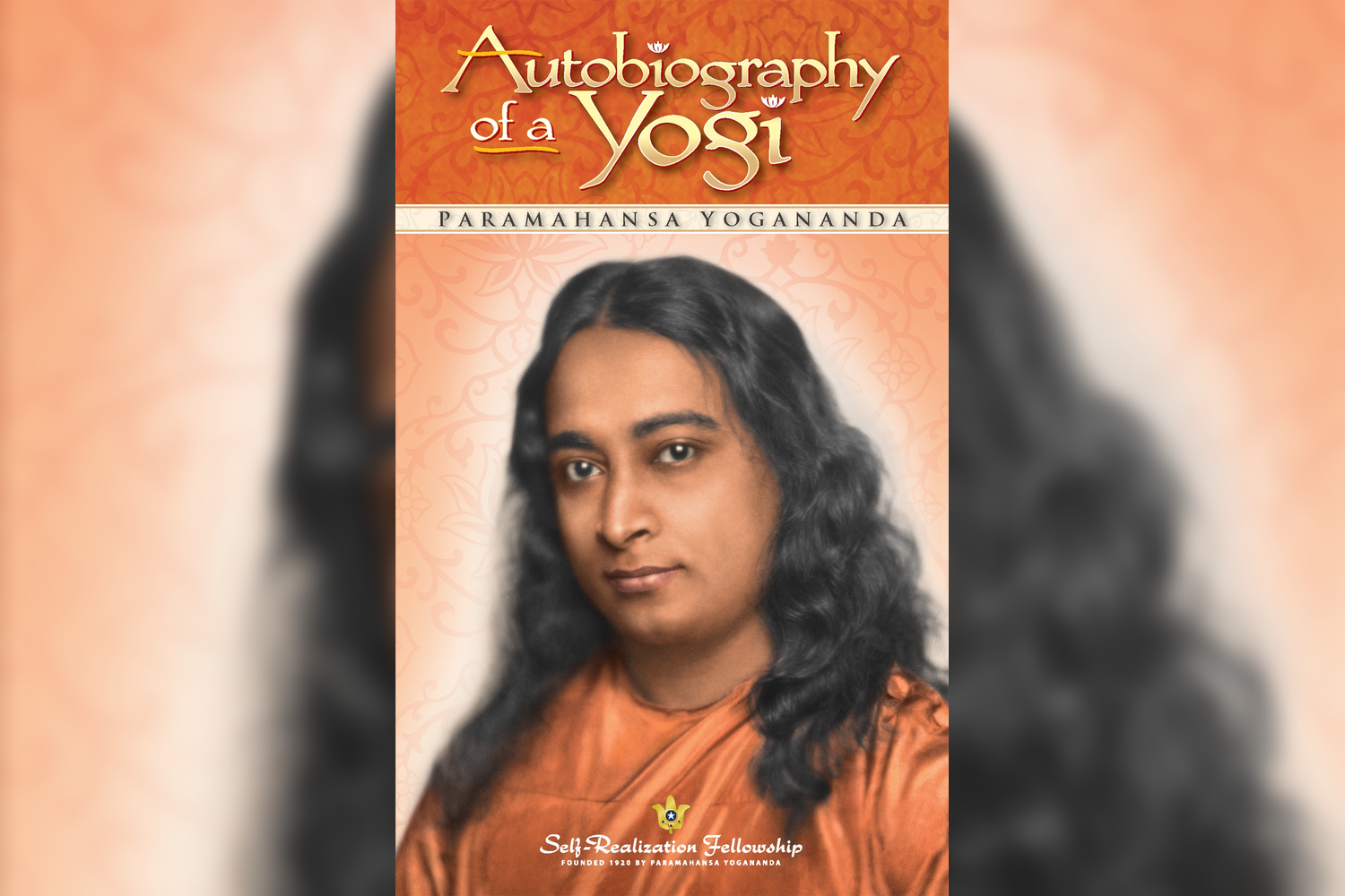 Book cover titled "Autobiography of a Yogi" by Paramahansa Yogananda, featuring a portrait of Paramahansa Yogananda with long, wavy black hair, wearing saffron robes, and a background with orange and gold decorative patterns. The bottom text reads "S