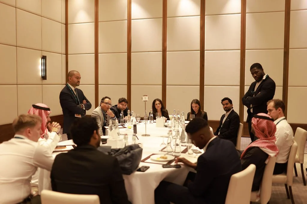 Business meeting with diverse professionals seated around a round table in a conference room.