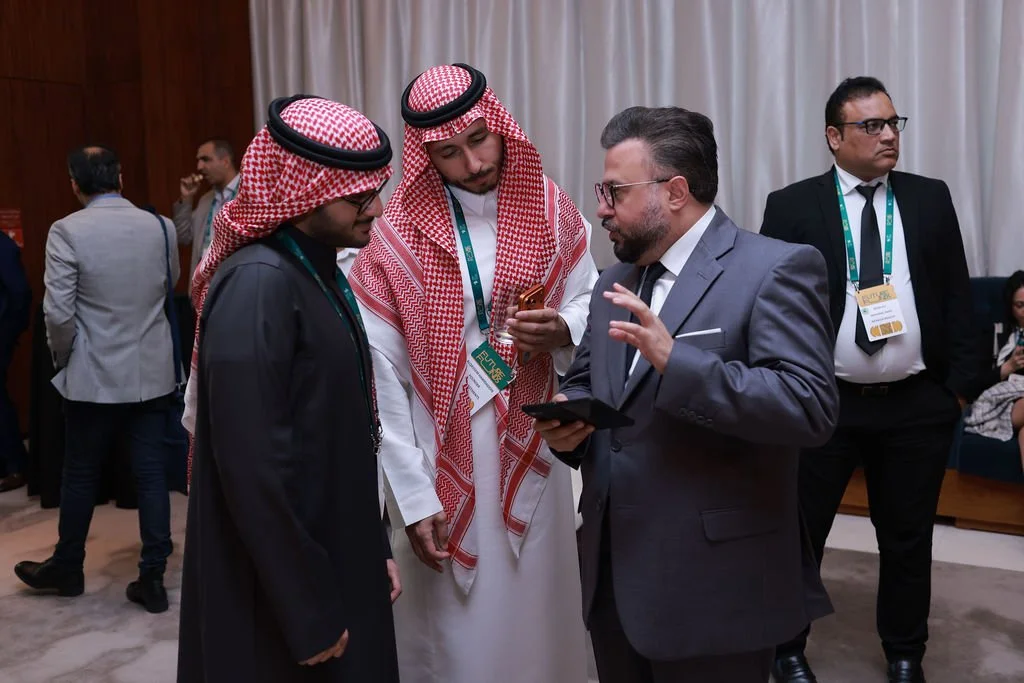 Businessmen having a discussion at a conference or event, with men in traditional Middle Eastern attire and one man in a suit