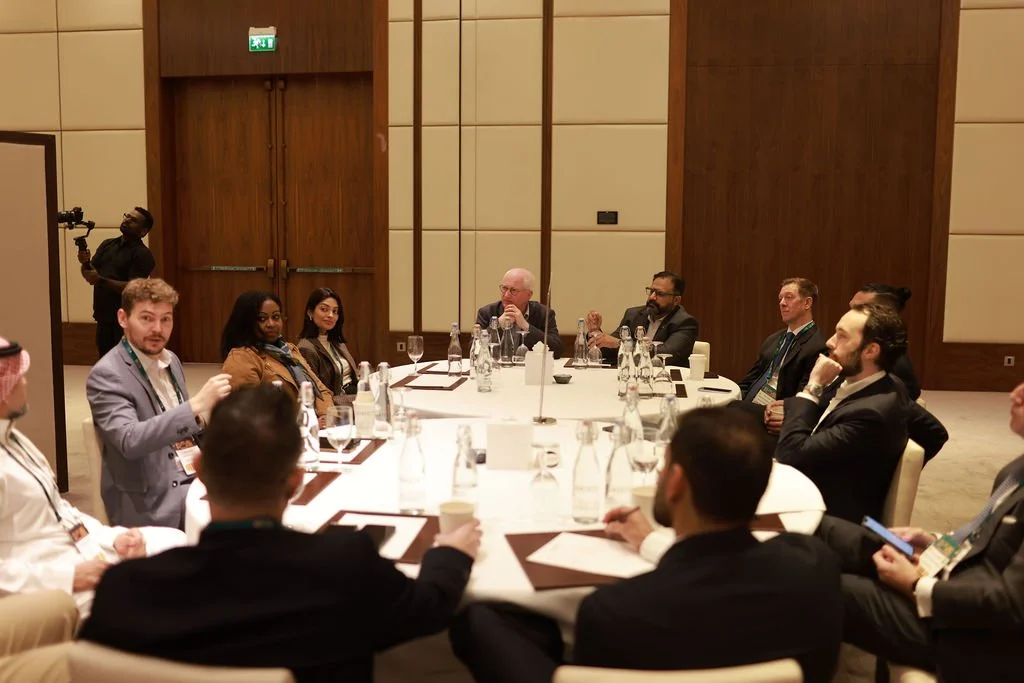 Business meeting with diverse professionals seated around a large round table in a conference room.