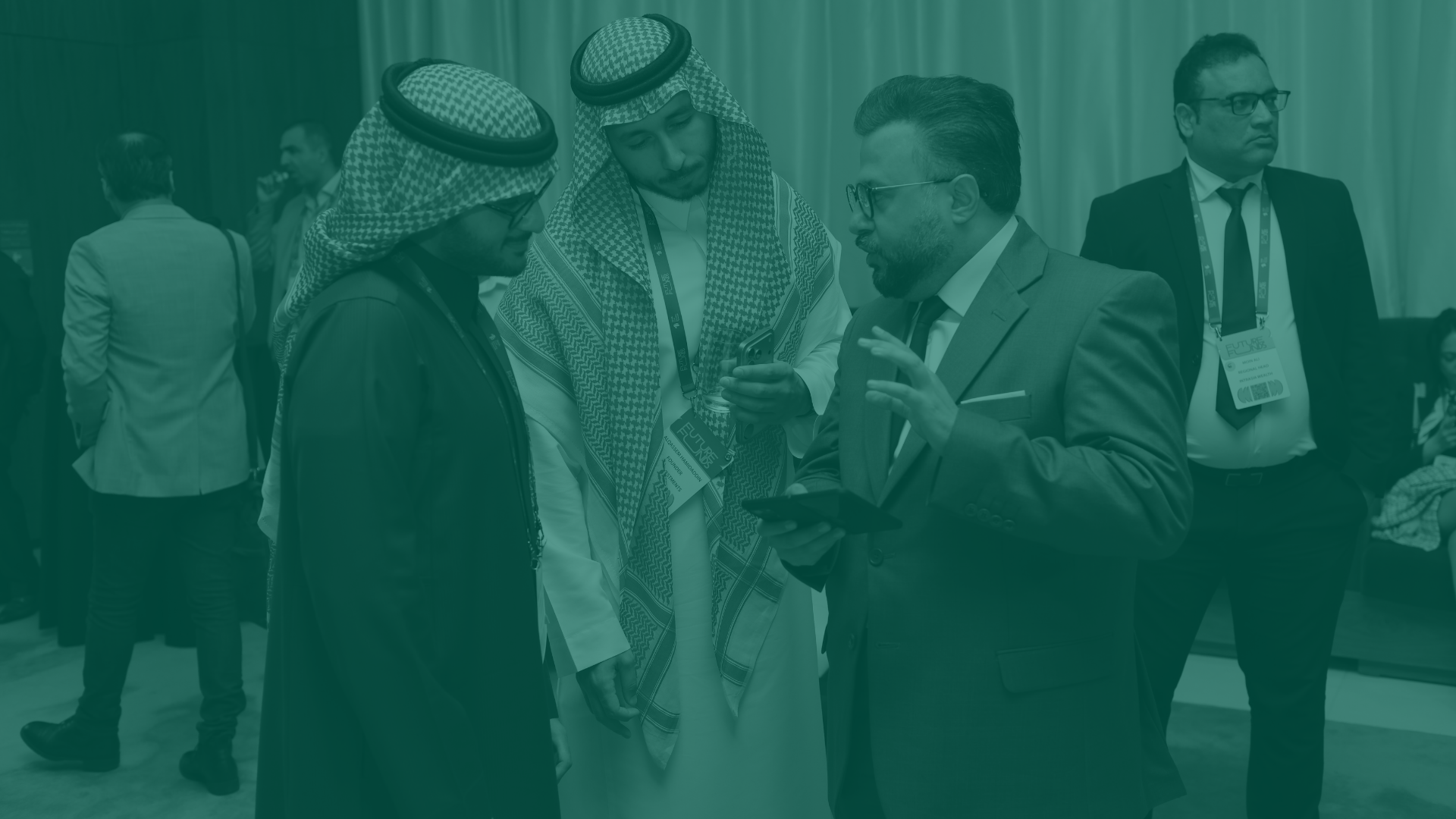 Group of men in business attire and traditional Middle Eastern clothing engaged in conversation at a conference or event.