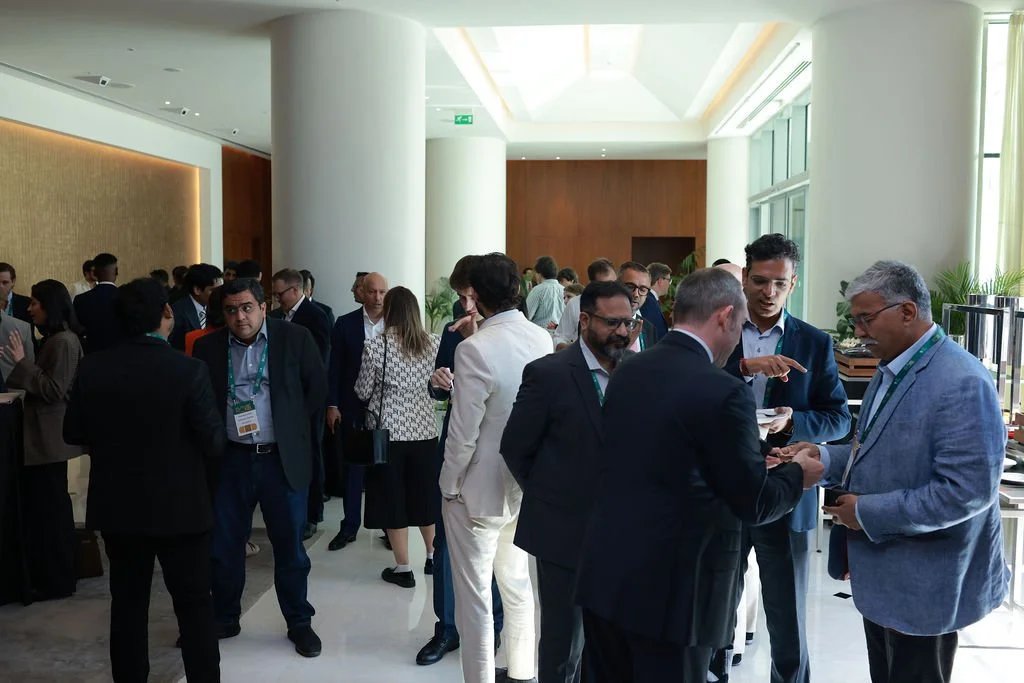 Business professionals socializing at a conference or networking event in a modern, well-lit venue.