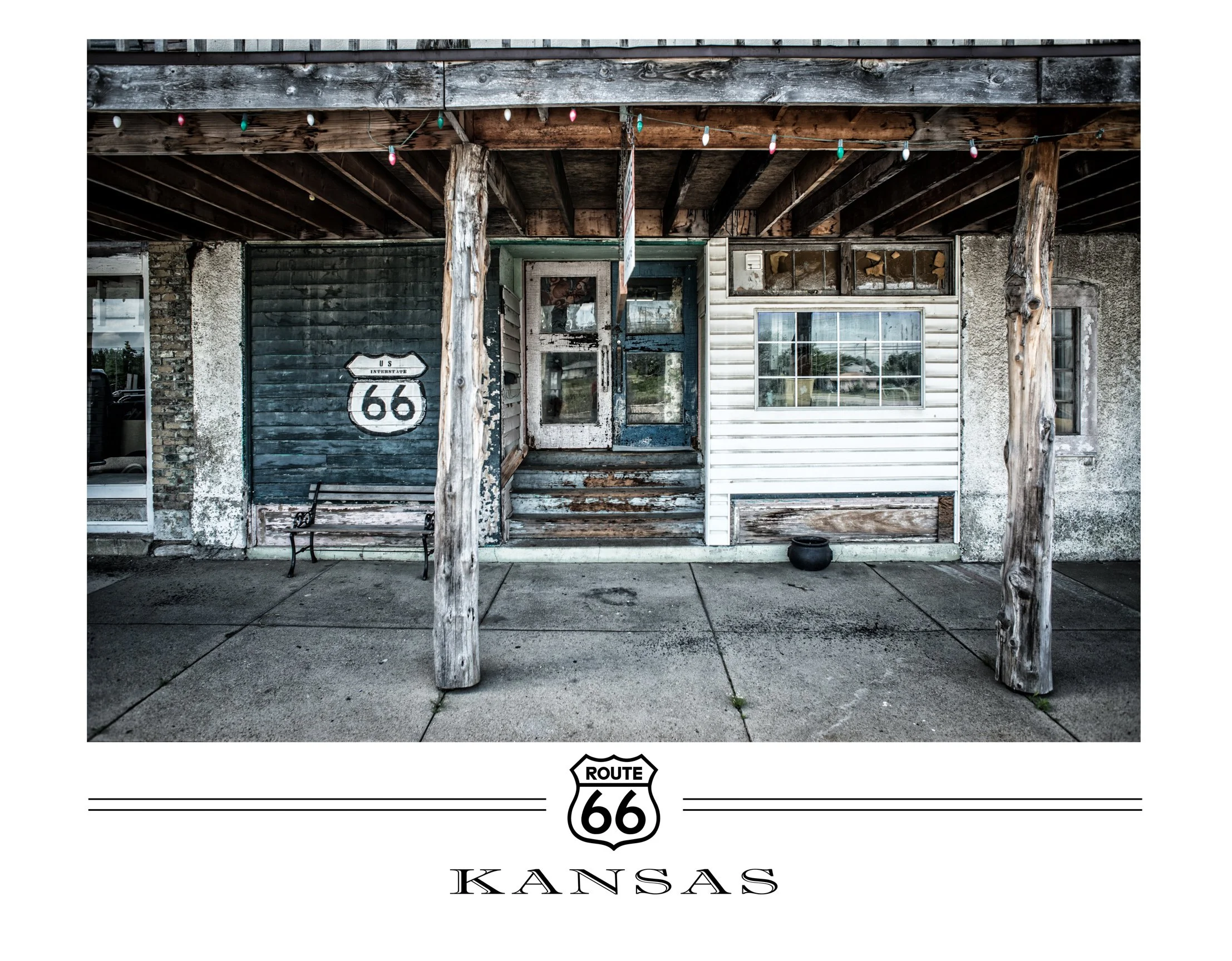 Facade of a rustic building on Route 66 in Kansas, with weathered wood and siding, a Windows, and a bench under a porch with string lights.