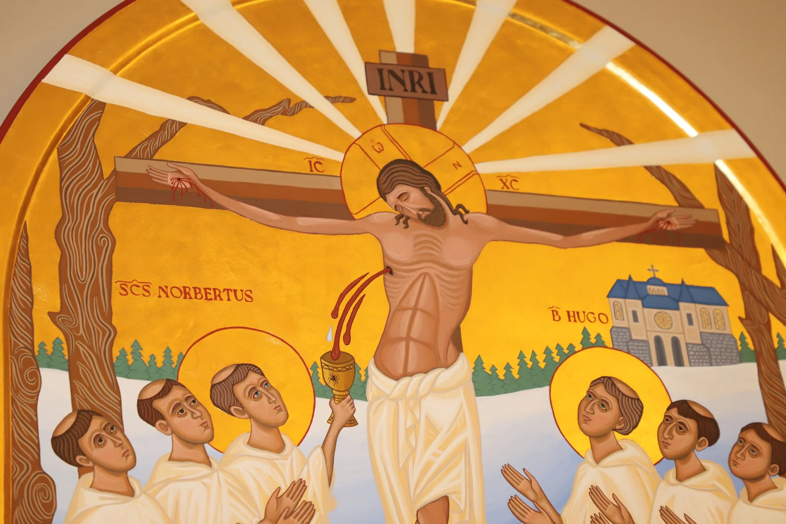 Christian iconographic artwork depicting Jesus Christ on the cross, with a halo around his head, surrounded by six Norbertines. The background includes trees and a church. The artwork features traditional colors with gold, brown, and white tones.