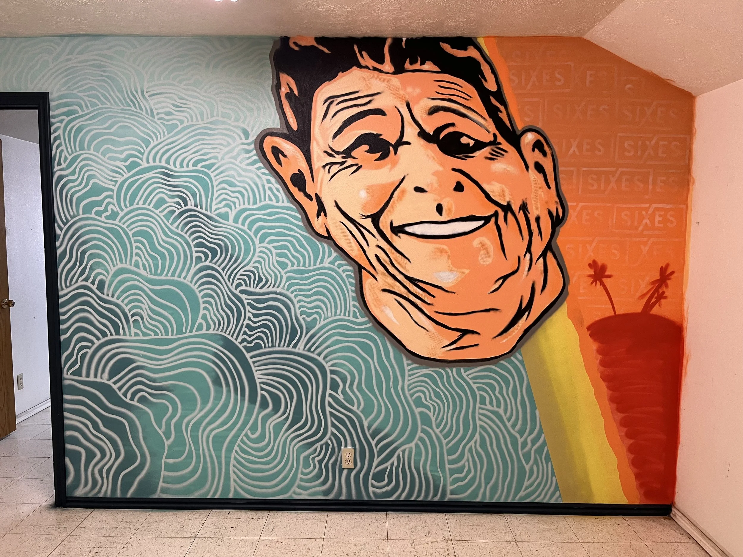 A large mural of a smiling elderly woman with glasses, painted in a pop art style, on a wall with a blue and white patterned background resembling waves or clouds. Next to it, an orange wall with the word 'SIXES' repeated in a grid pattern, and a red