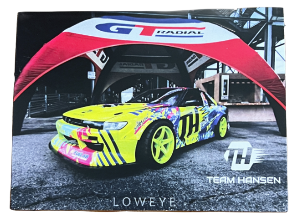 Colorful race car with the number 11 and bright yellow wheels, parked under a red GT Federal tent with Team Hansen branding.