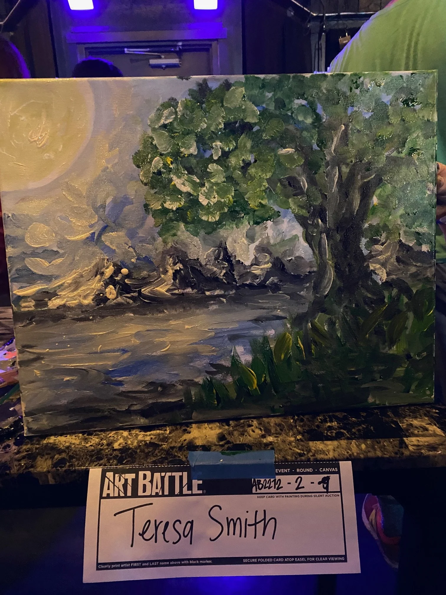 A painting of a lush green tree with a thick trunk, painted with textured brushstrokes on a canvas. The background features a partly cloudy sky, and the artwork is set against a dark environment.