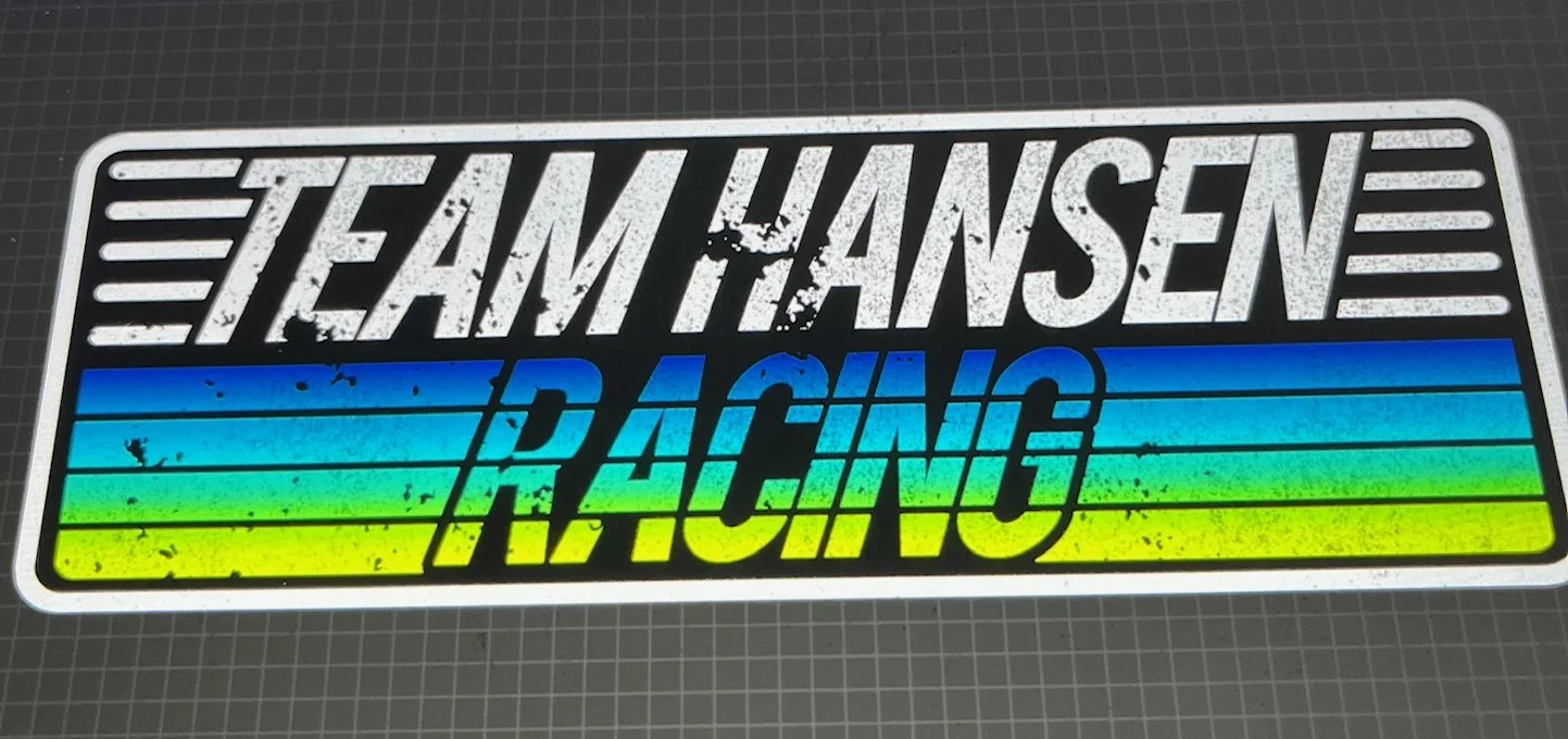 Sticker reading 'Team Hansen Racing' with a rainbow-colored background and distressed white text and black text overlay.