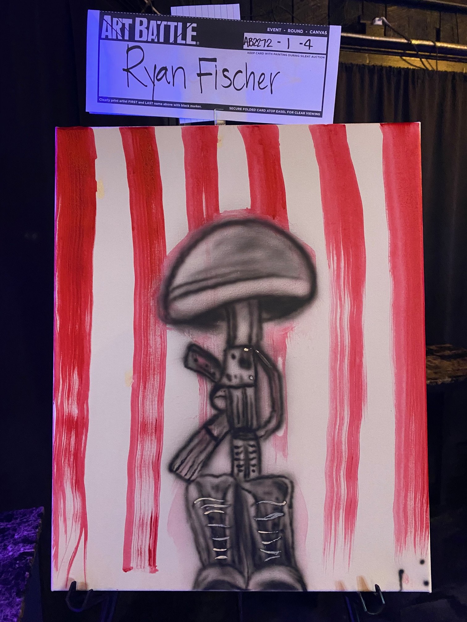 Painted canvas with red vertical stripes and a black outlined cartoon skeleton in the foreground. A sign above indicates it is part of an art battle event, with the artist's name, Ryan Fischer, written on it.