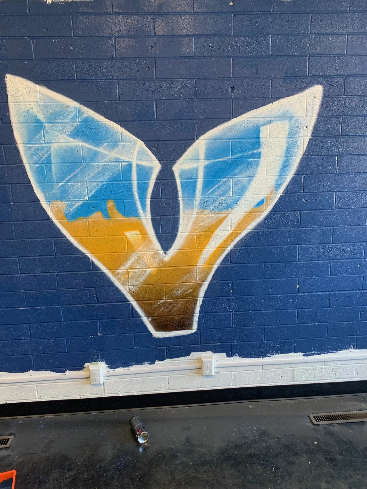 Graffiti of a butterfly painted on a dark blue brick wall.
