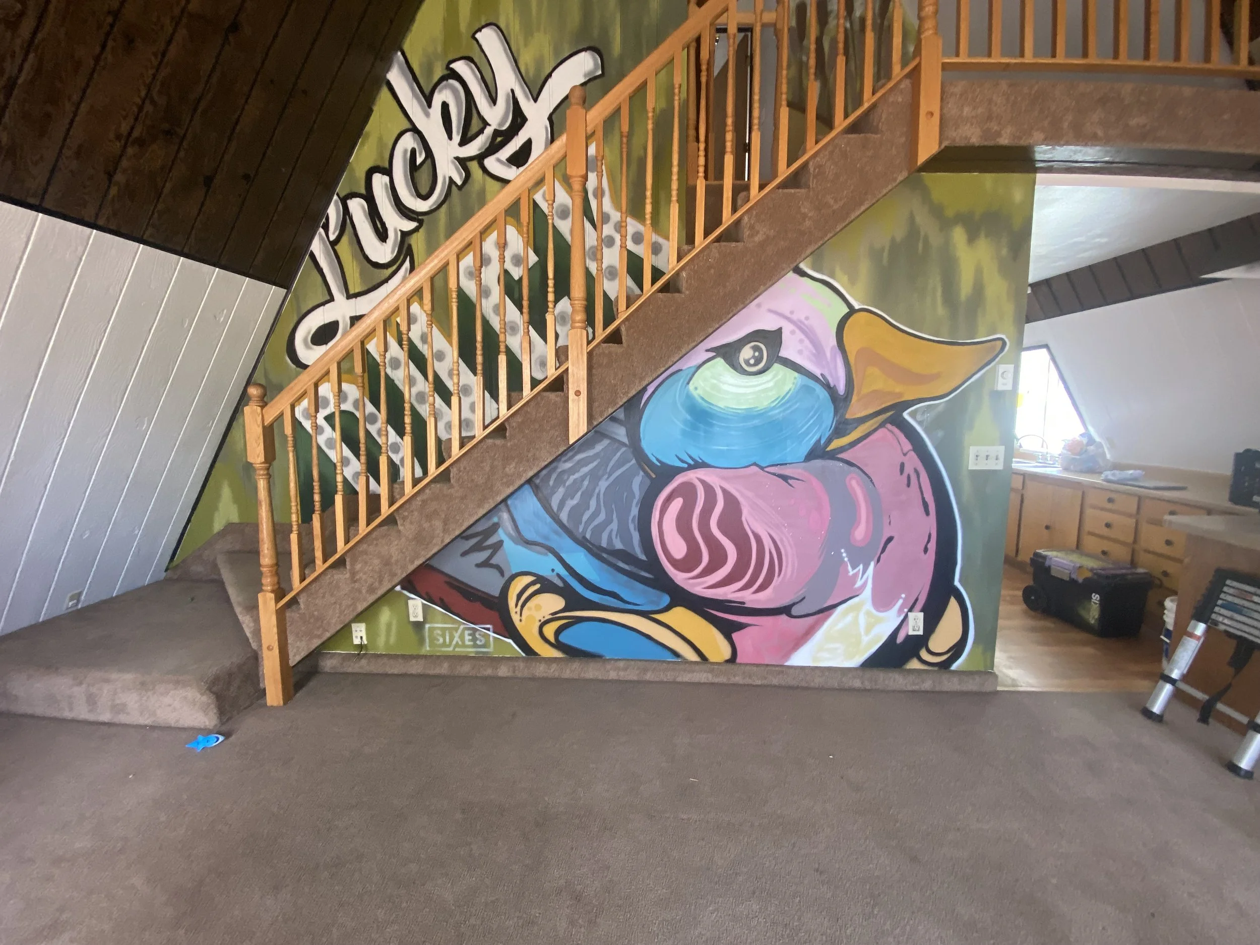 Colorful mural featuring a stylized dog or wolf in pink, purple, blue, and yellow colors, with the word 'puzzle' in large white and black letters on a green background, visible on the wall behind a wooden staircase in a cozy room.
