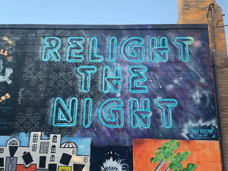Neon sign on a brick wall reading 'Religion is a Light' in blue letters.