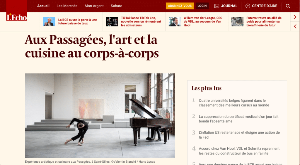 A person performing a dance move in an art gallery with a grand piano and art on the walls.