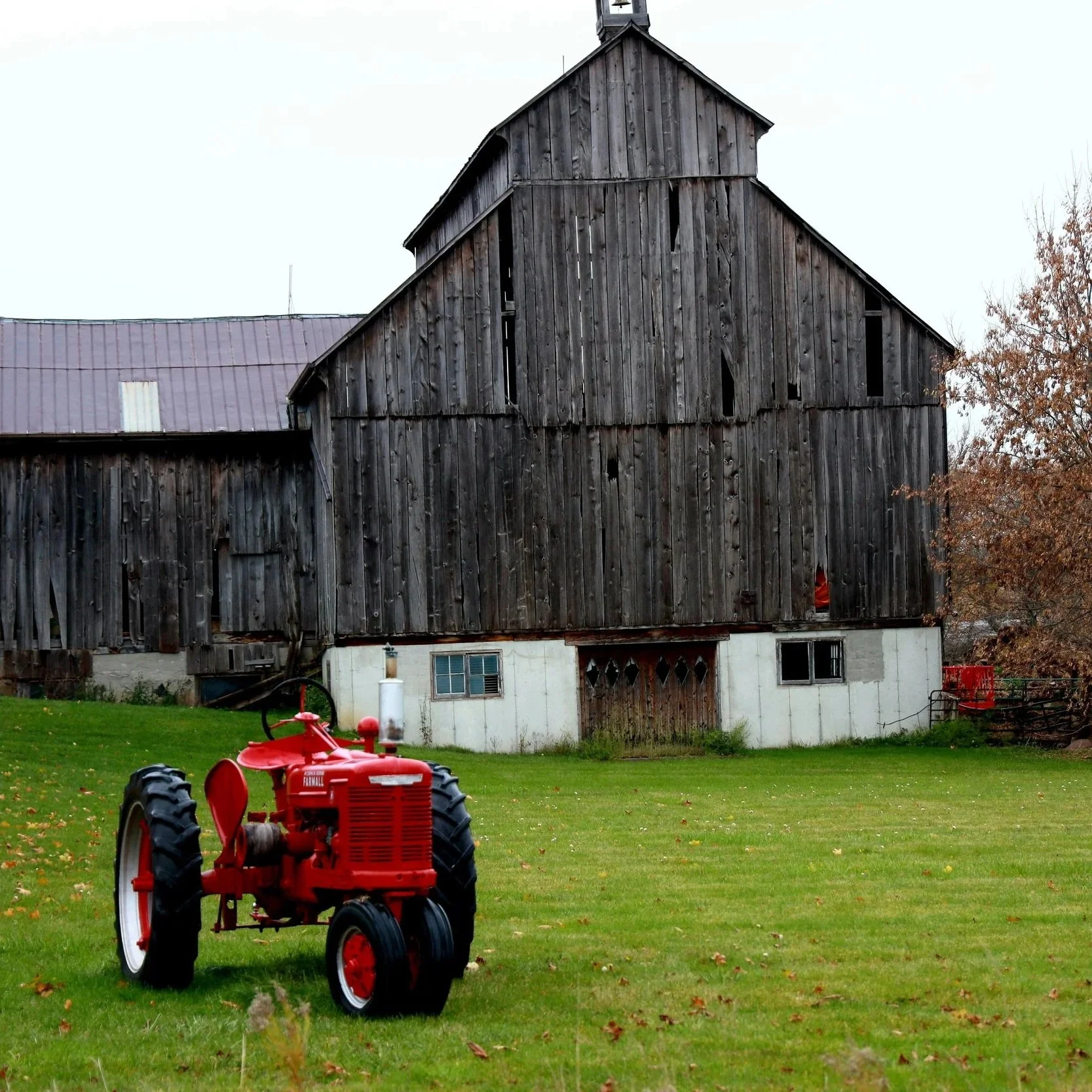 Farm landscape with a tractor in a field representing farm insurance coverage for agricultural property and equipment.
