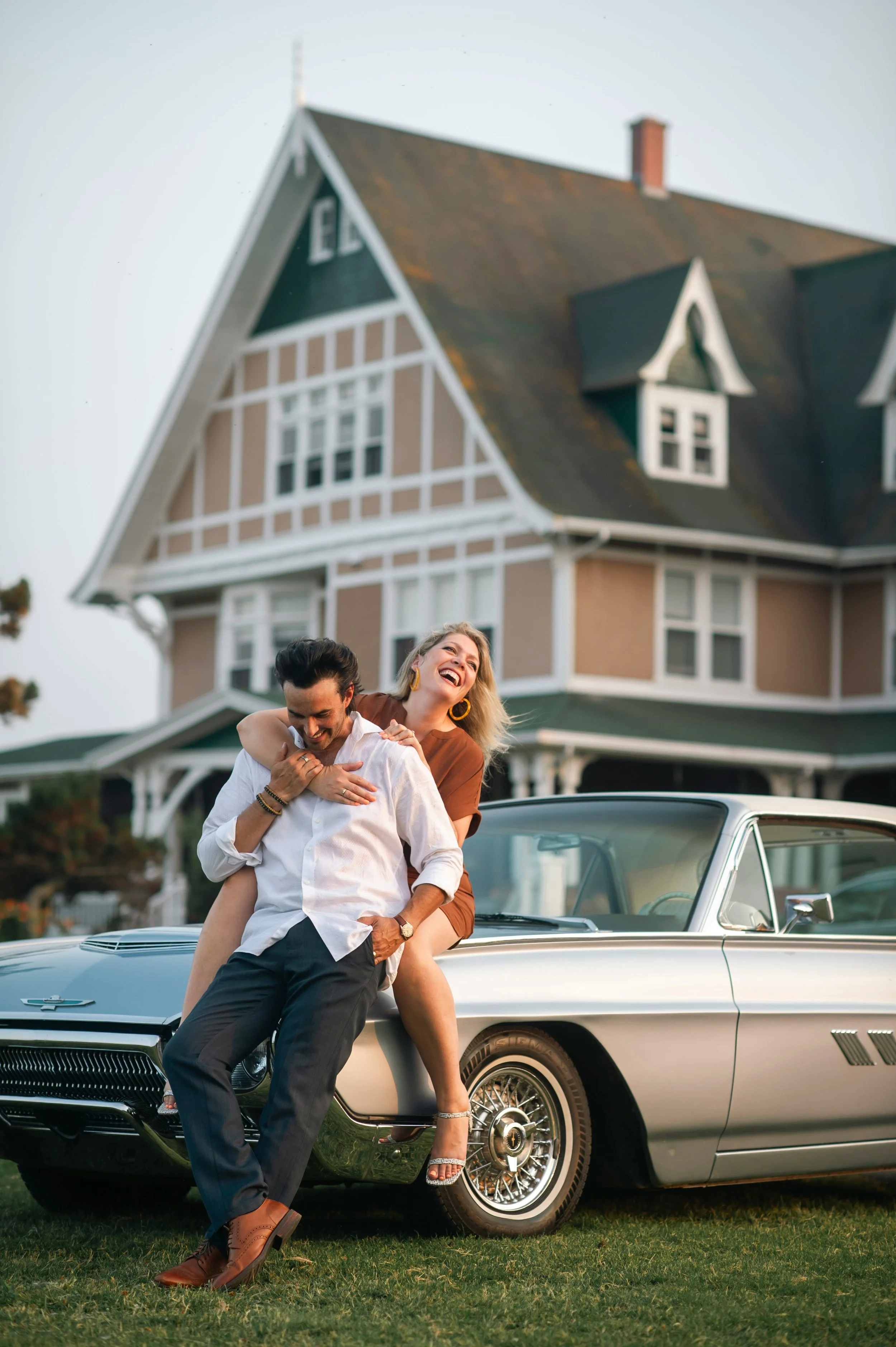 Husband and wife on car in front of house