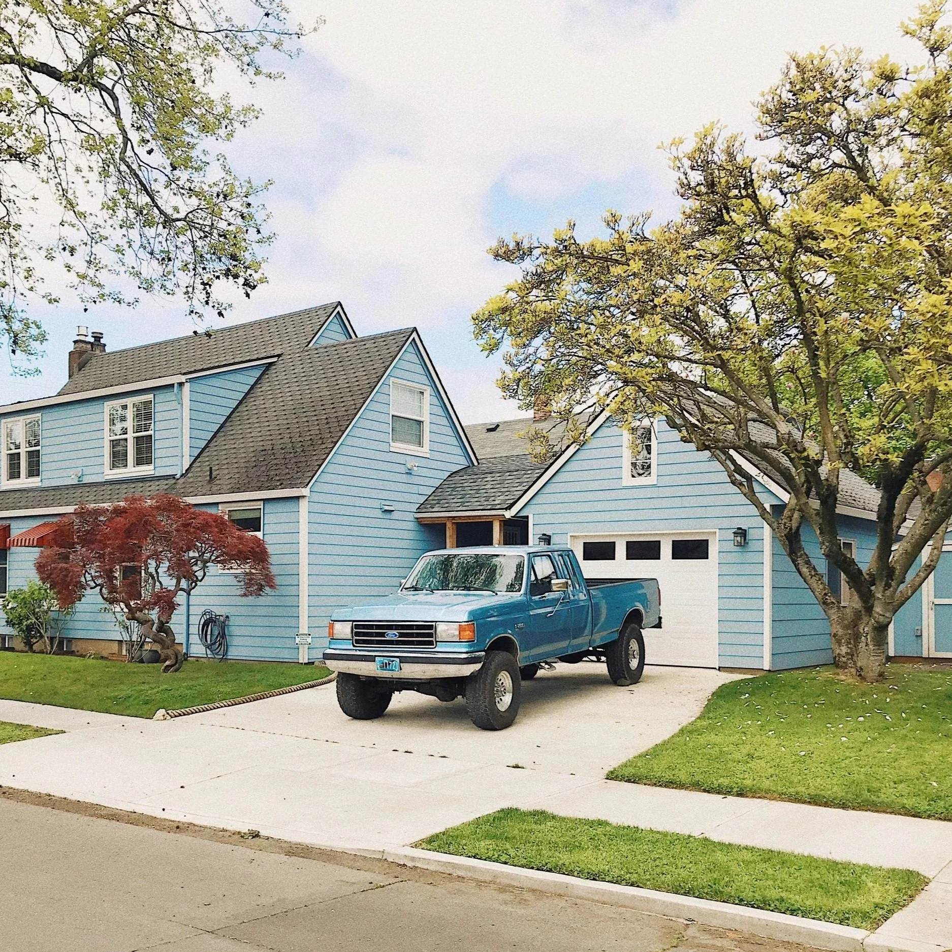 Exterior view of a residential home and vehicle representing personal insurance coverage for homeowners, auto, and families.