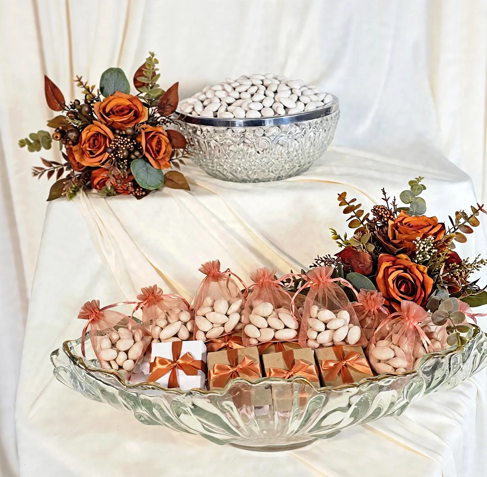 Glass bowls with white candies, gift boxes, and orange rose floral accents