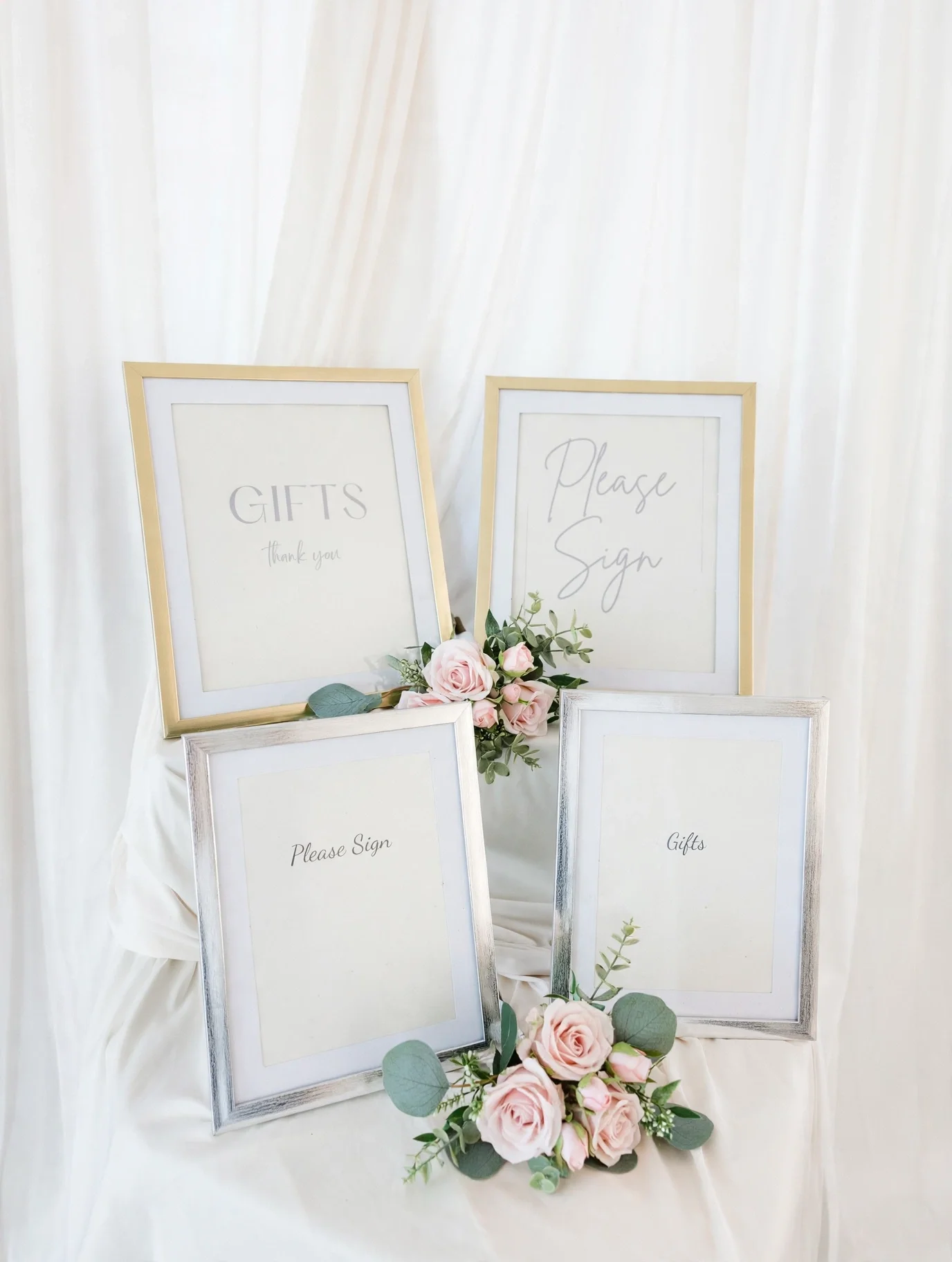Gold and silver framed gift and sign prints with pink roses and greenery on white draped fabric