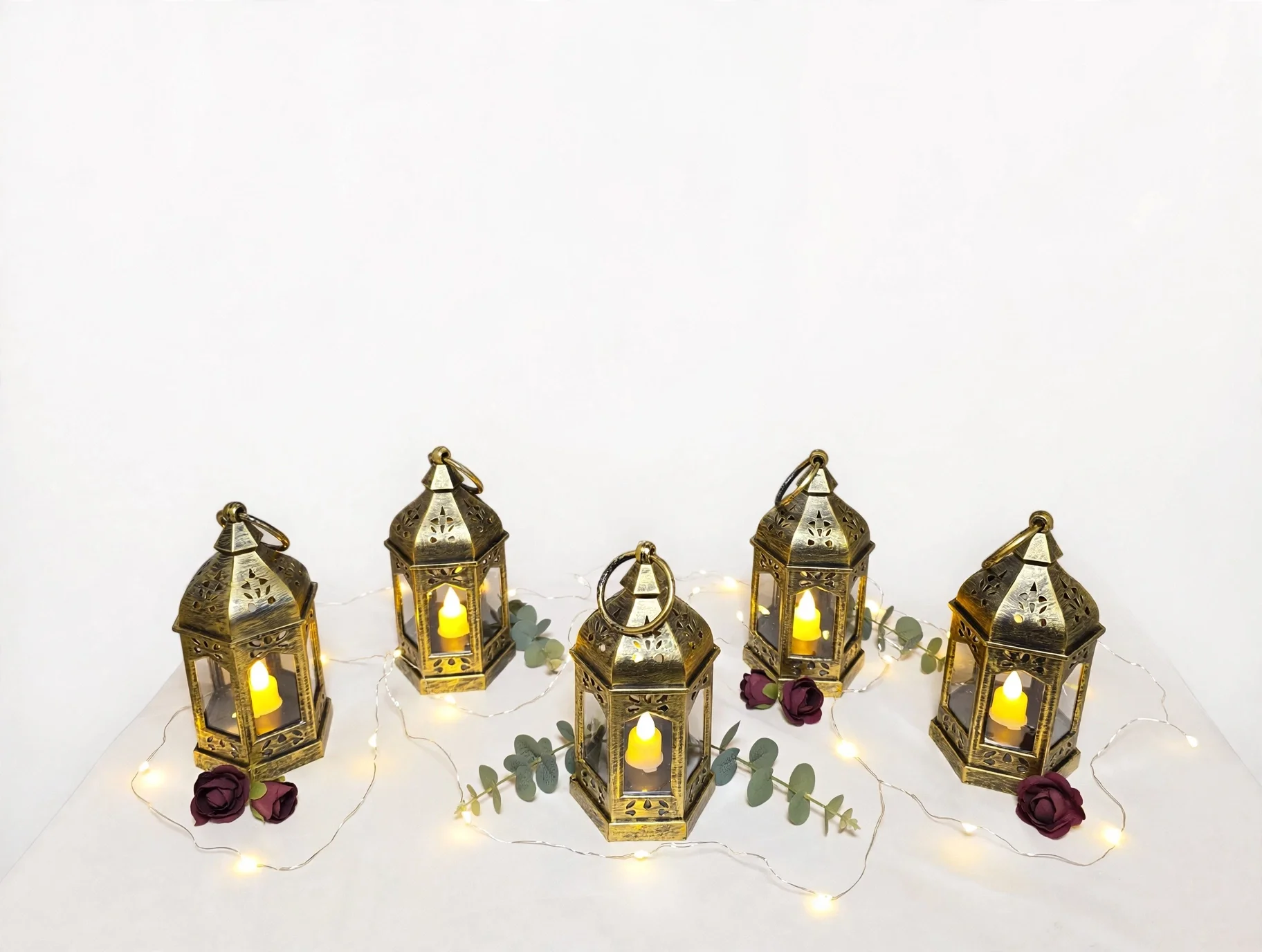 5 vintage gold lantern with glowing candle, roses, eucalyptus, and scattered petals