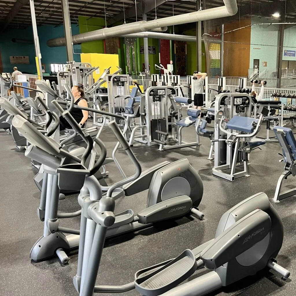 Inside the WIS gym with various exercise machines, including ellipticals, bikes, and strength training equipment.