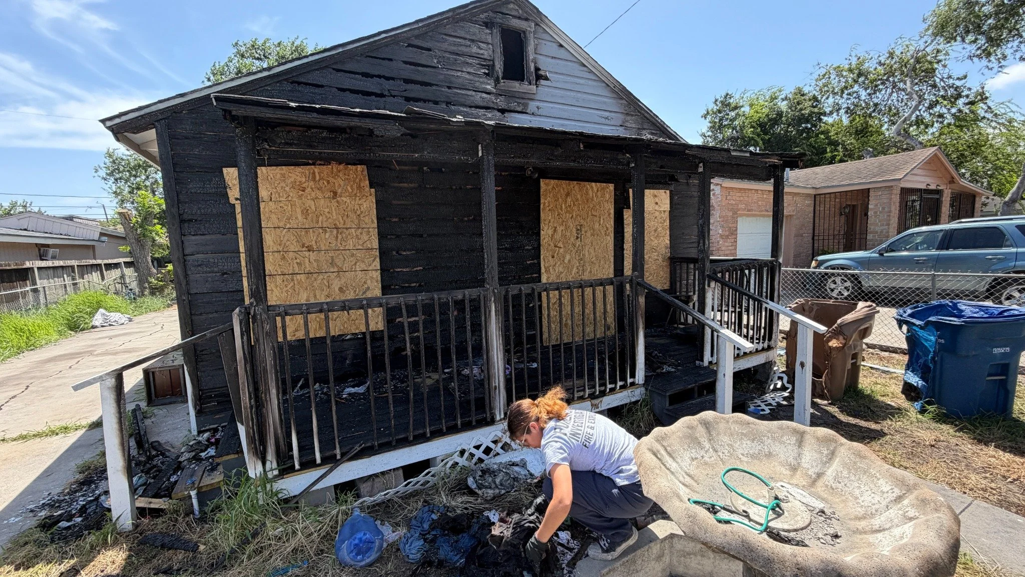 Fire investigator examining debris outside a fire-damaged residential structure.