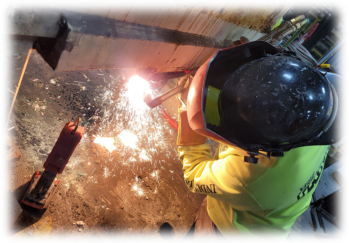 Worker welding metal with sparks flying in an industrial workshop.