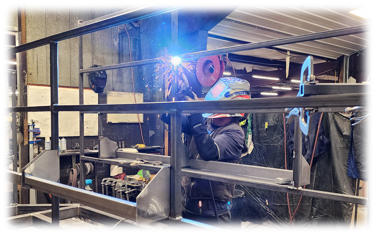 Worker in welding helmet welding metal frame in a workshop.
