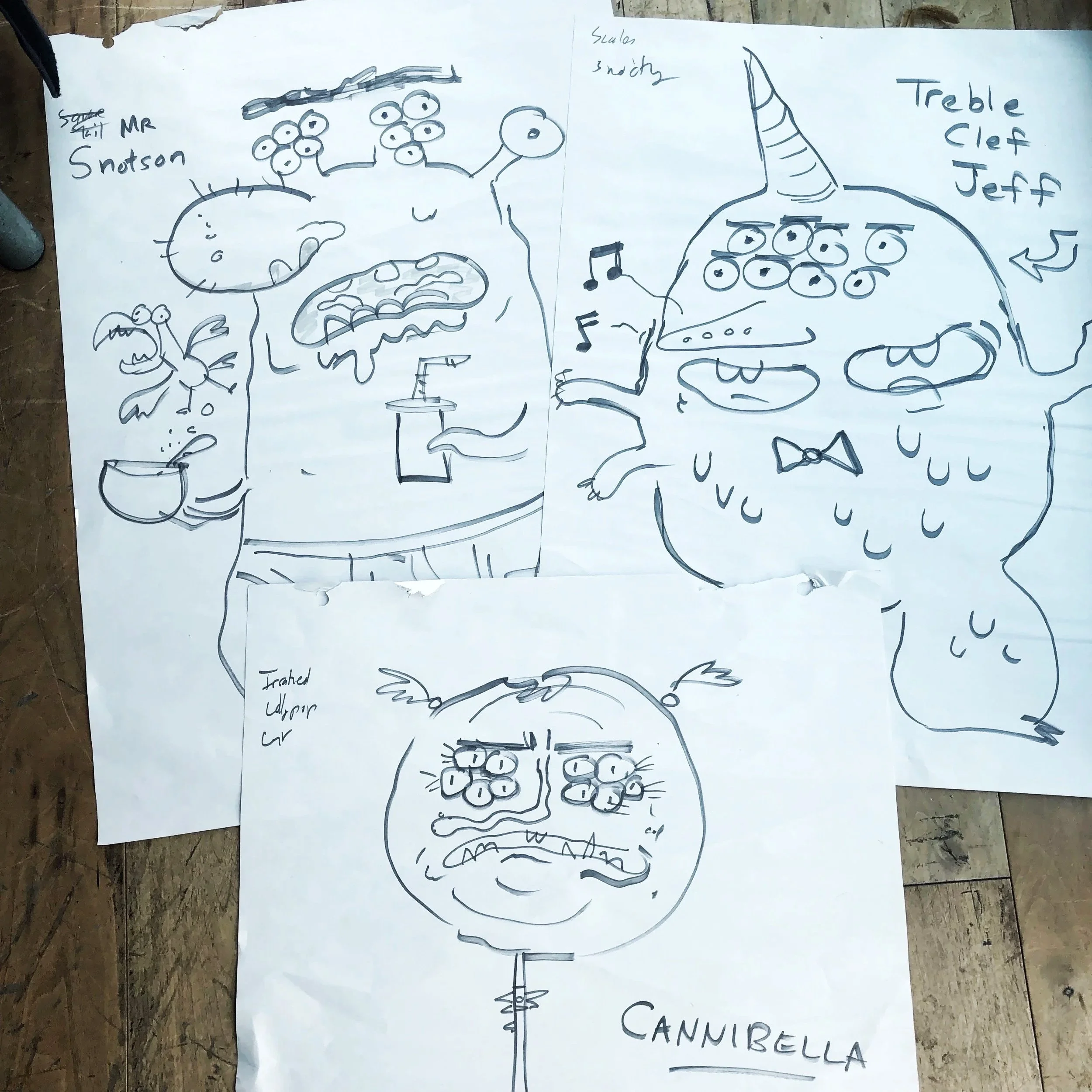 A hand-drawn poster on paper displays a musical staff with a treble clef, notes, and a cartoonish creature with multiple eyes and a tail, with text indicating a dedication to Jeff.
