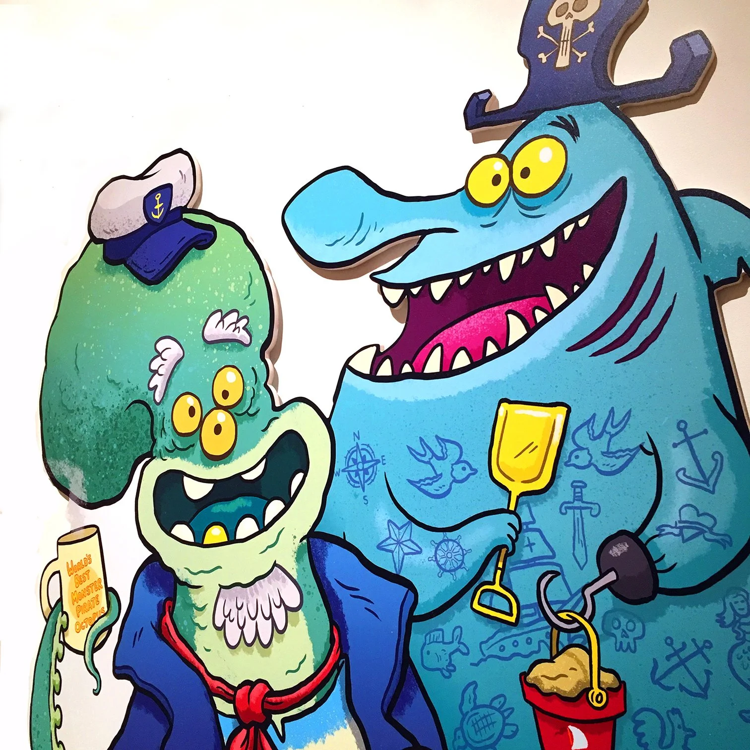 Colorful drawing of two cartoon sea monsters dressed as pirates. The monster on the left is green with three yellow eyes, wearing a pirate hat, and has a speech bubble that says "World's best monster pirate Octopus." The monster on the right is blue with yellow eyes, wearing a pirate hat with a skull, and has tattoos of anchors, fish, and other nautical symbols on its body. It is holding a plunger connected to a red bucket.
