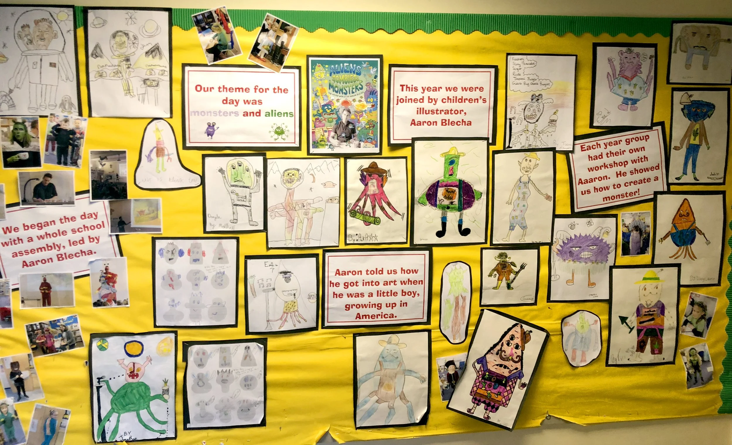 Display board featuring children's artwork and photographs, with posters highlighting a theme about monsters and aliens, created by kids for a school project.