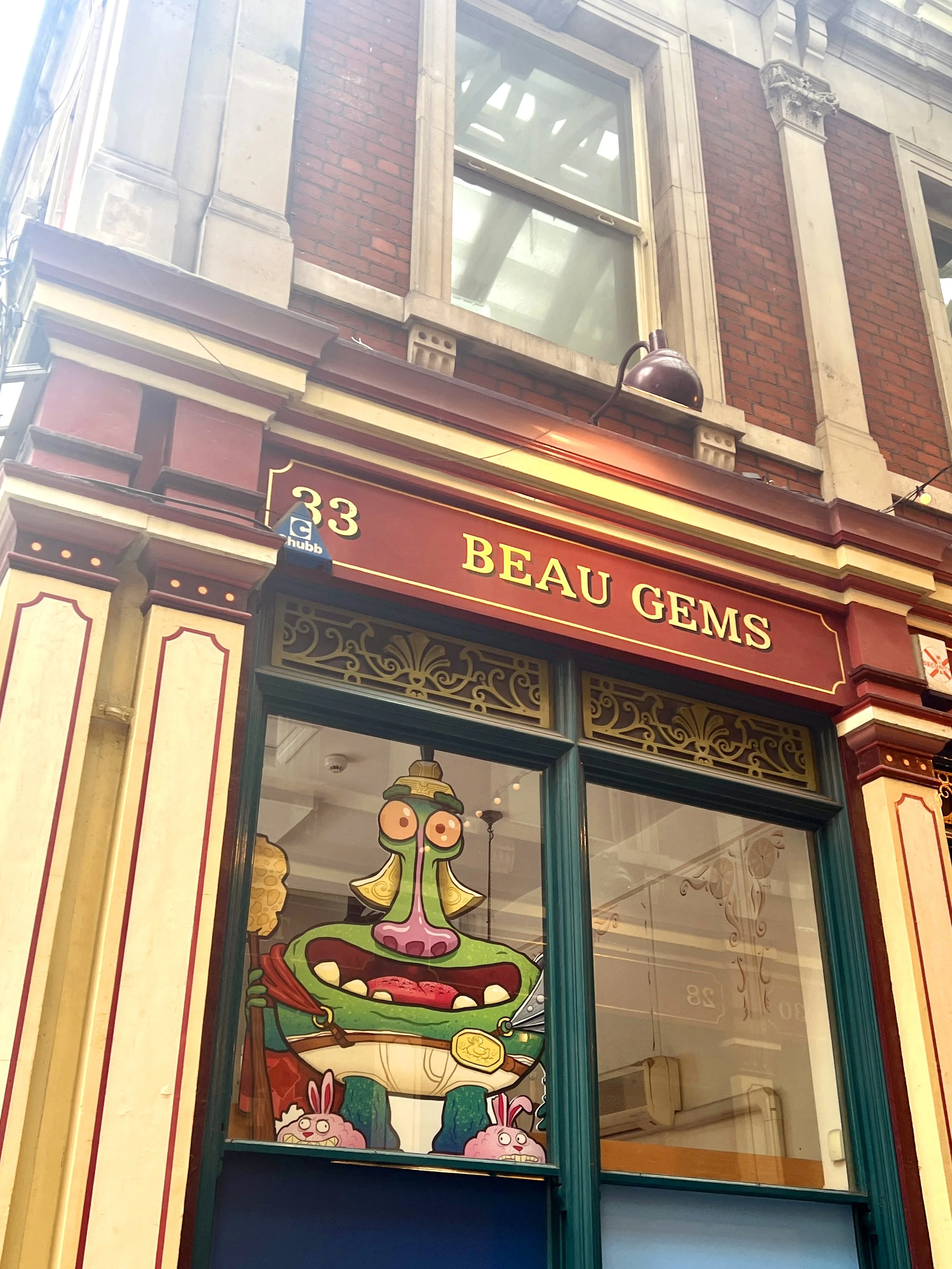 Storefront for Beau Gems with decorative window display featuring cartoon characters, including a green creature with pink nose and other animals, in a colorful and artistic design.