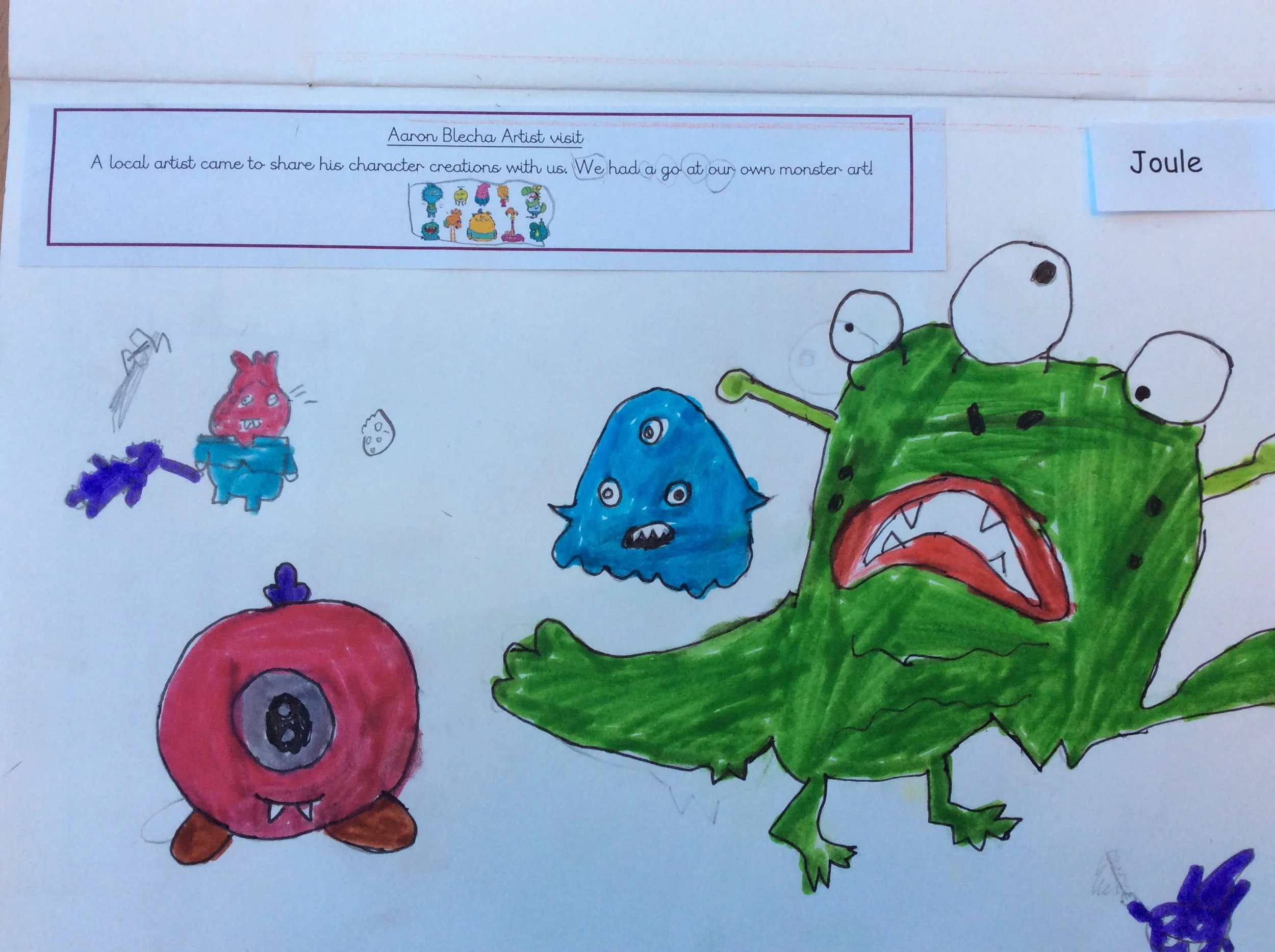 Colorful hand-drawn illustration of various monsters and fantasy creatures, including a large green monster with an open mouth and sharp teeth, a blue three-eyed monster, a pink creature with small horns, and smaller monsters around them. The drawing appears on a white sheet of paper.